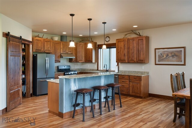 kitchen with stainless steel refrigerator, stove, a barn door, and light wood-type flooring