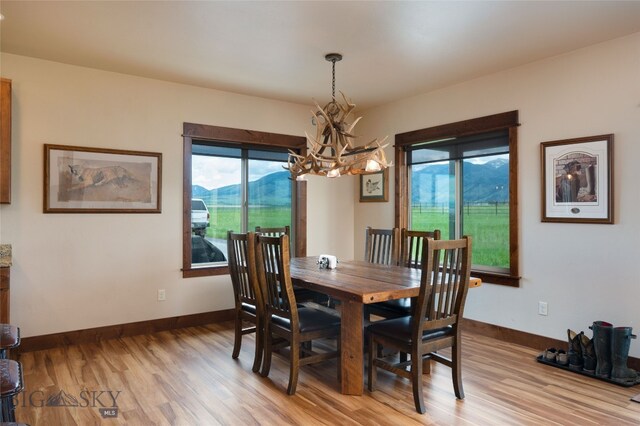 dining space with wood-type flooring, a mountain view, and an inviting chandelier