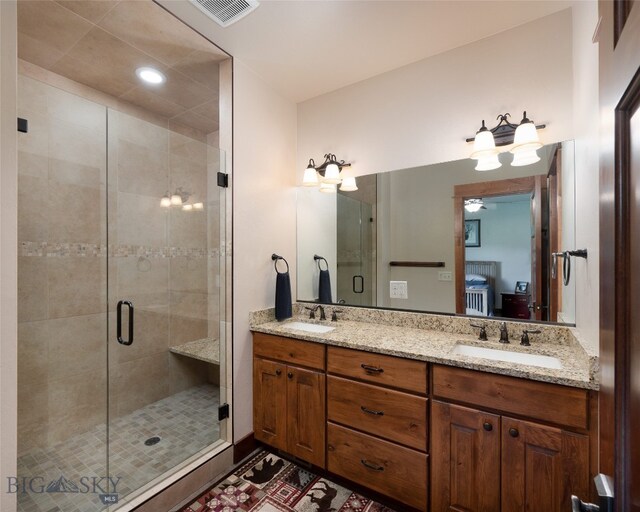 bathroom with a shower with shower door and double sink vanity