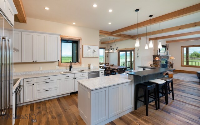 kitchen featuring decorative light fixtures, white cabinets, beamed ceiling, sink, and dark hardwood / wood-style flooring