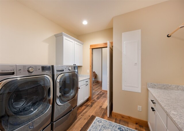 washroom featuring cabinets, light wood-type flooring, and washing machine and clothes dryer