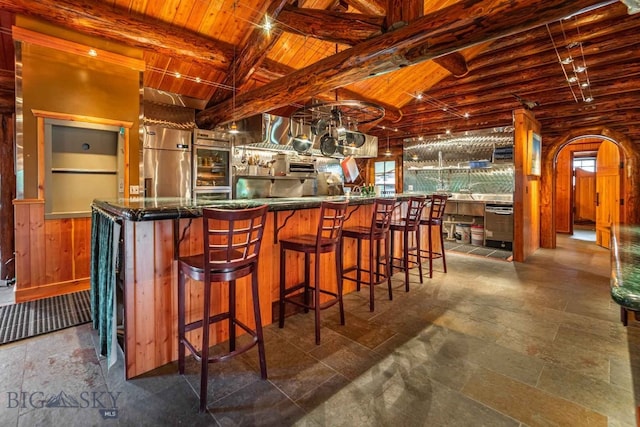 bar with beam ceiling, dark tile floors, and stainless steel fridge