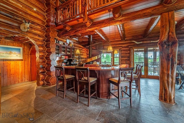 interior space featuring log walls, beam ceiling, dark tile floors, and kitchen peninsula