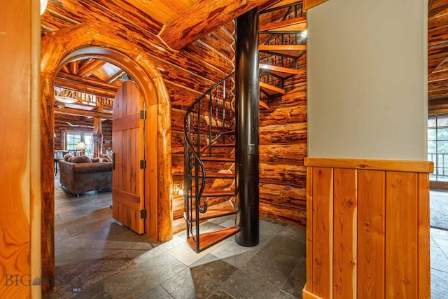 stairway featuring log walls, plenty of natural light, tile floors, and wooden ceiling