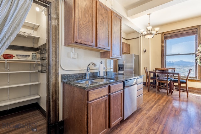 kitchen featuring stainless steel appliances, dark hardwood / wood-style flooring, pendant lighting, a chandelier, and sink