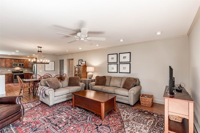 living room with ceiling fan with notable chandelier, crown molding, and hardwood / wood-style floors