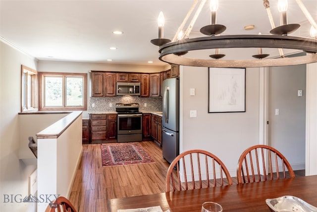 kitchen featuring ornamental molding, tasteful backsplash, appliances with stainless steel finishes, and wood-type flooring