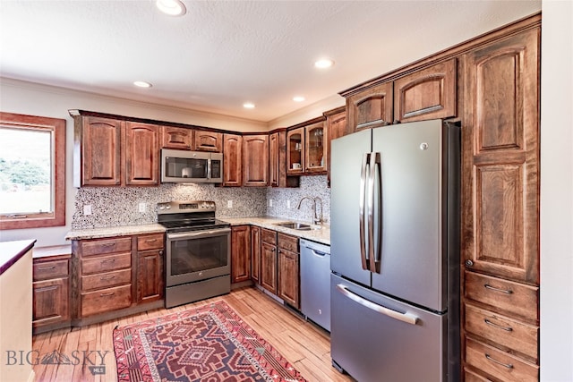 kitchen with tasteful backsplash, stainless steel appliances, sink, and light wood-type flooring