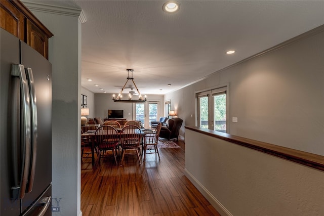 dining area with ornamental molding, a notable chandelier, and dark wood-type flooring