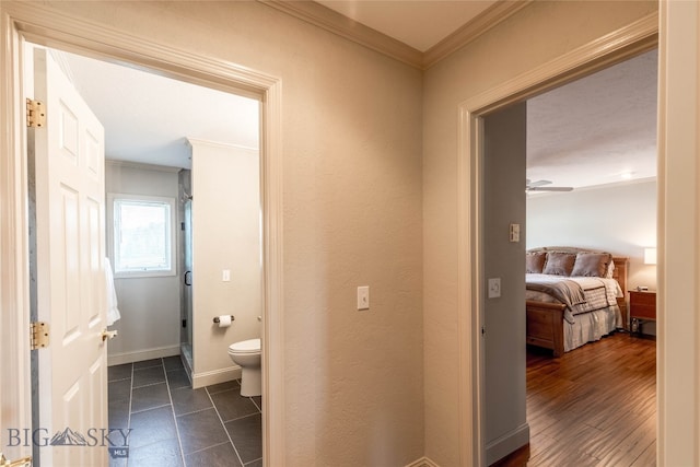 hallway with crown molding and dark tile flooring