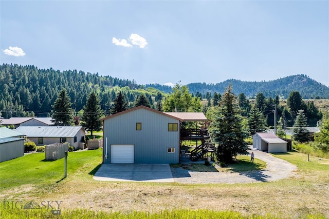 back of house with a mountain view, a yard, an outdoor structure, and a garage