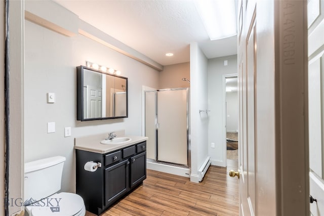 bathroom with hardwood / wood-style flooring, a shower with shower door, toilet, and vanity