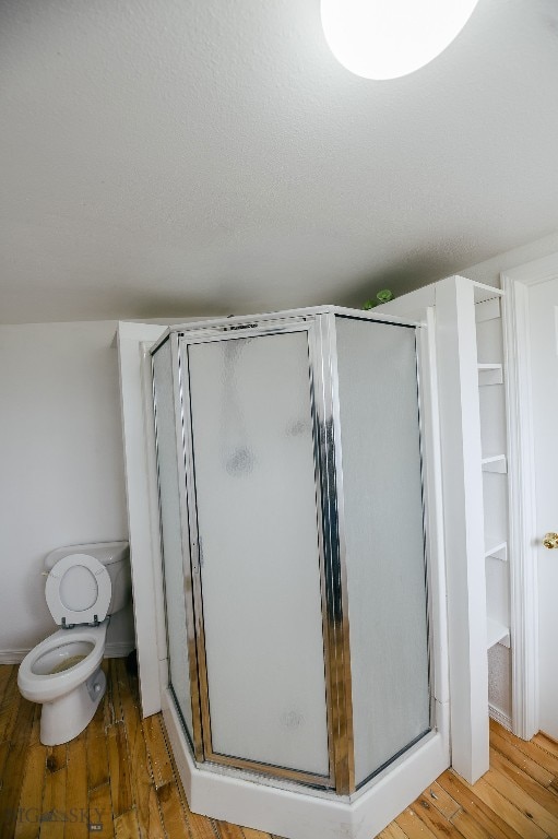 bathroom featuring an enclosed shower, toilet, and hardwood / wood-style flooring