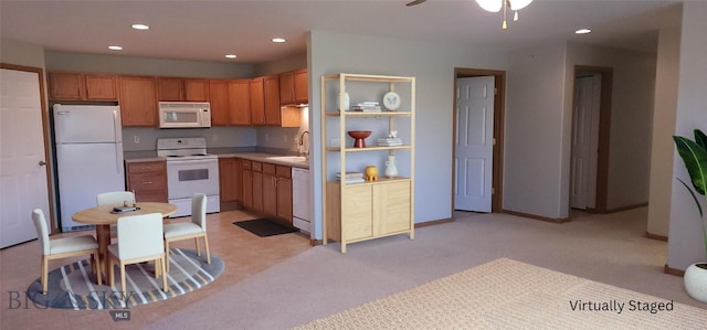 kitchen with sink, white appliances, light colored carpet, and ceiling fan