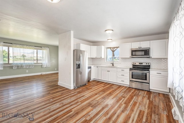 kitchen featuring white cabinetry, sink, decorative backsplash, light hardwood / wood-style floors, and stainless steel appliances