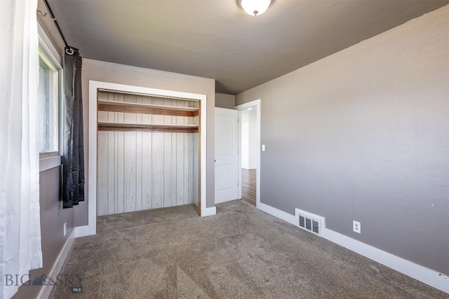 unfurnished bedroom with carpet floors, a closet, and wood walls