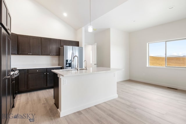 kitchen featuring light wood-type flooring, pendant lighting, stainless steel appliances, an island with sink, and sink