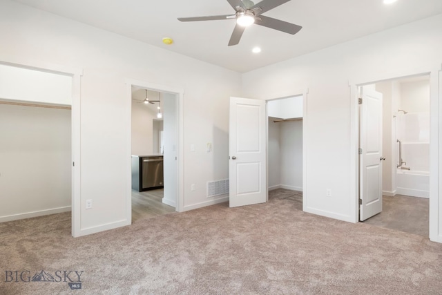 unfurnished bedroom with ensuite bath, light carpet, two closets, and ceiling fan