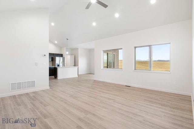 unfurnished living room with high vaulted ceiling, ceiling fan, and light wood-type flooring