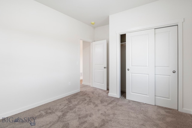 unfurnished bedroom with light colored carpet and a closet