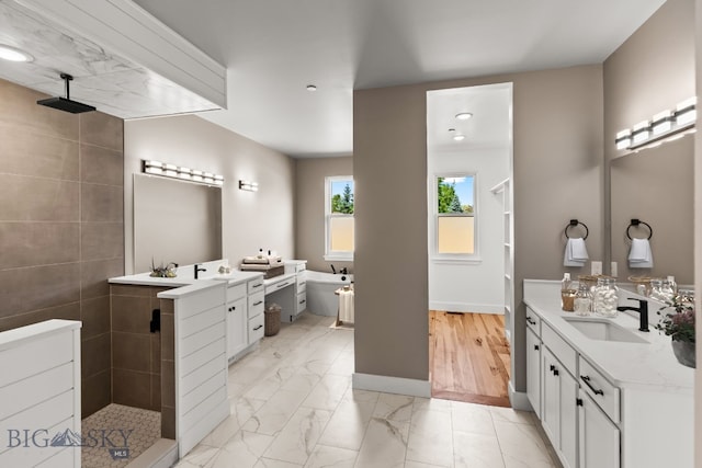 bathroom featuring baseboards, marble finish floor, walk in shower, a freestanding bath, and vanity