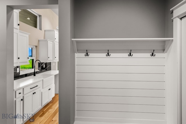 mudroom with sink and light hardwood / wood-style flooring