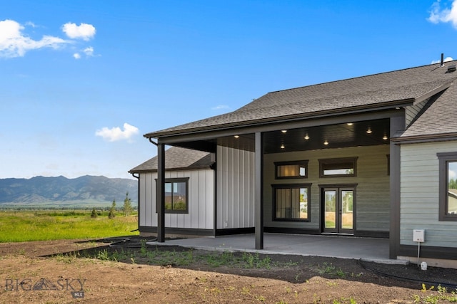 back of property with a mountain view and a patio