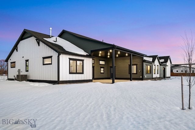 snow covered rear of property with board and batten siding