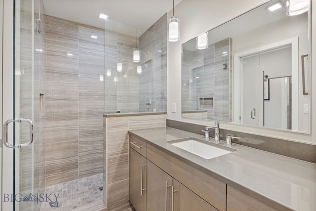 bathroom featuring a shower with door and vanity