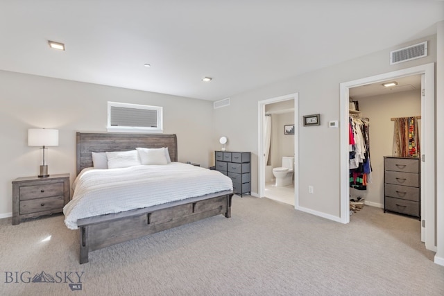 bedroom featuring connected bathroom, a walk in closet, a closet, and carpet floors