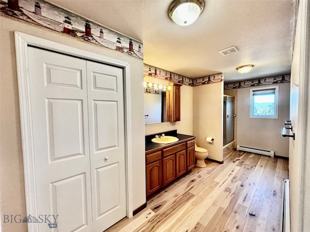 kitchen with light hardwood / wood-style floors, sink, a baseboard heating unit, and a textured ceiling