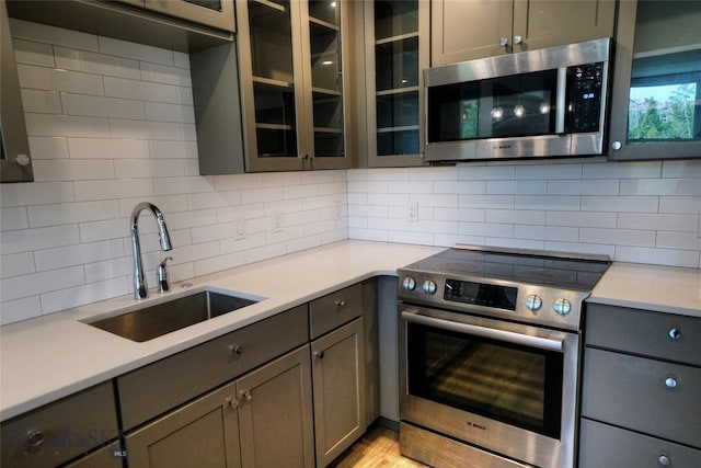 kitchen with light wood-type flooring, stainless steel appliances, sink, and decorative backsplash