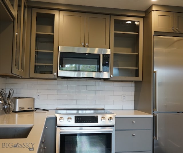 kitchen featuring gray cabinets, appliances with stainless steel finishes, and tasteful backsplash