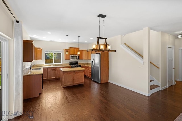 kitchen with a center island, hanging light fixtures, light stone countertops, appliances with stainless steel finishes, and dark hardwood / wood-style flooring