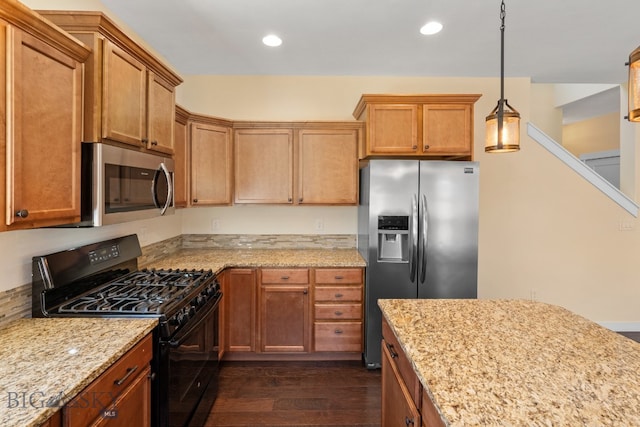 kitchen with light stone counters, dark hardwood / wood-style floors, decorative light fixtures, and appliances with stainless steel finishes