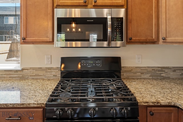 kitchen with black gas range, light stone countertops, and a healthy amount of sunlight