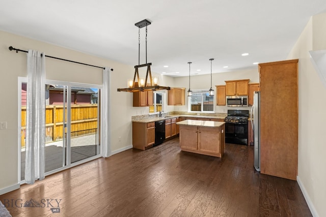 kitchen featuring dark hardwood / wood-style flooring, black appliances, pendant lighting, a notable chandelier, and a kitchen island