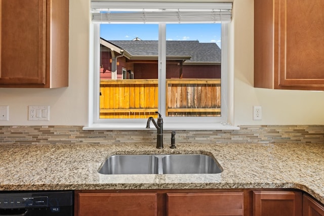 kitchen featuring black dishwasher, light stone counters, and sink