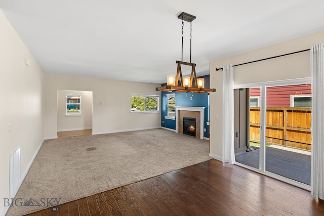 unfurnished living room featuring a tiled fireplace and dark wood-type flooring