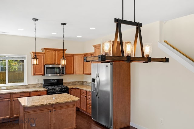 kitchen with light stone countertops, pendant lighting, stainless steel appliances, and a kitchen island