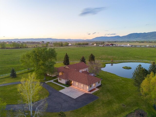 aerial view at dusk featuring a mountain view and a rural view