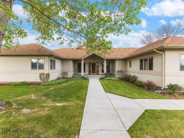 ranch-style house featuring a shingled roof, a front yard, and stucco siding