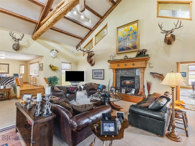 carpeted living room with high vaulted ceiling, beamed ceiling, and a glass covered fireplace