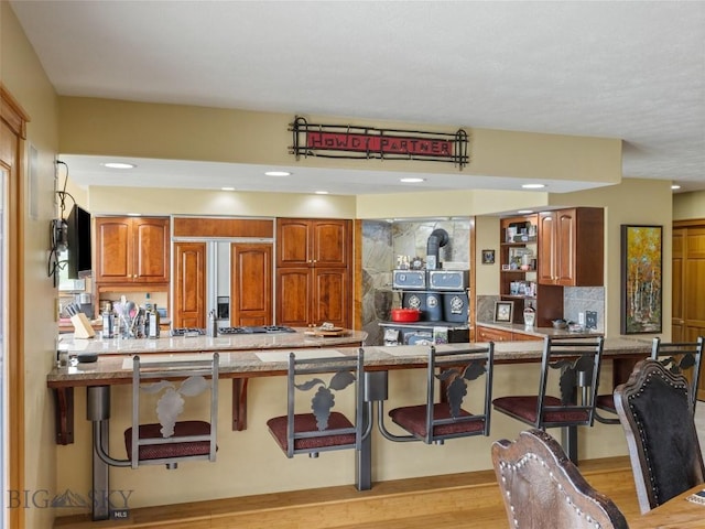 kitchen featuring a wood stove, tasteful backsplash, brown cabinets, and a breakfast bar