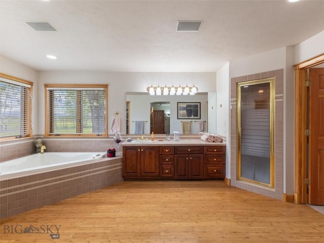 full bathroom featuring visible vents, wood finished floors, vanity, a shower stall, and a bath