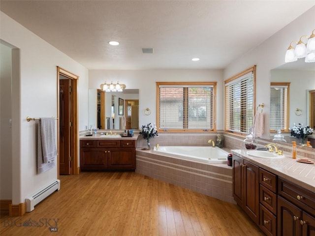 full bathroom with a garden tub, visible vents, baseboard heating, vanity, and wood finished floors