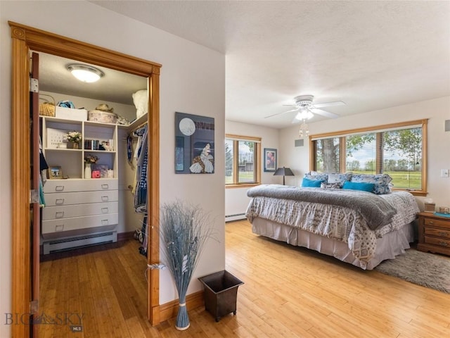 bedroom featuring multiple windows, hardwood / wood-style floors, and baseboard heating