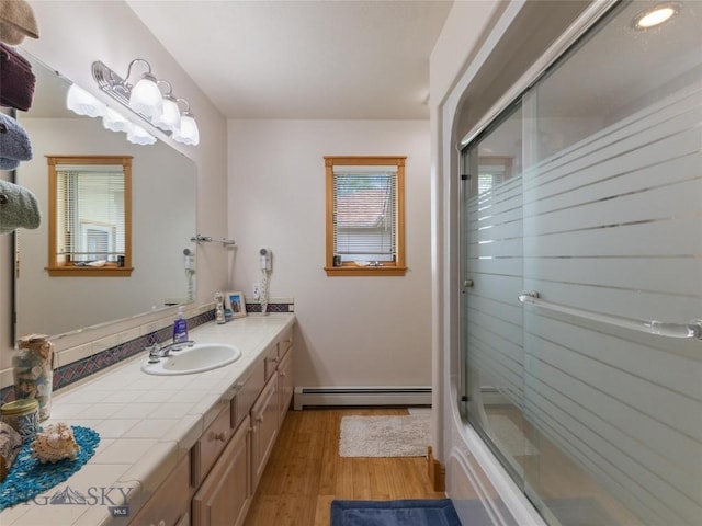 full bathroom featuring a baseboard radiator, wood finished floors, and vanity