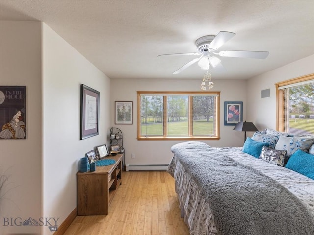 bedroom with baseboard heating, baseboards, ceiling fan, and light wood finished floors