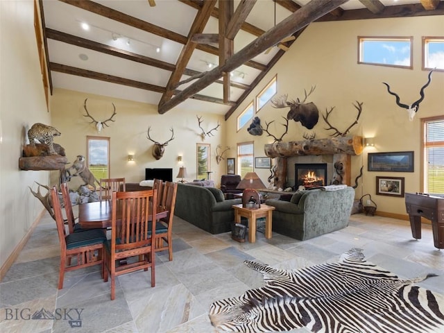 dining space with high vaulted ceiling, beamed ceiling, plenty of natural light, and a glass covered fireplace